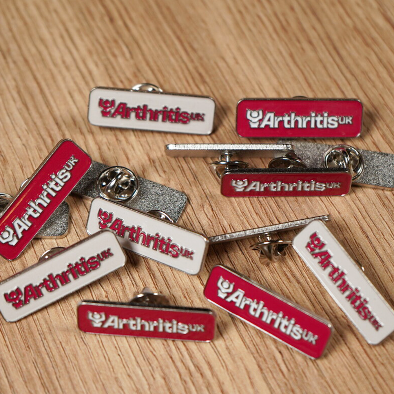 Collection of Arthritis UK pins on a wooden surface