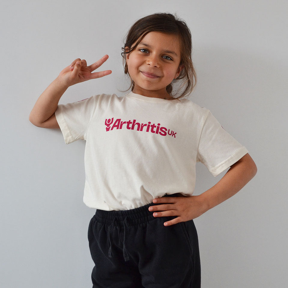 Child wearing a white t-shirt with 'Arthritis UK' Logo on a plain background