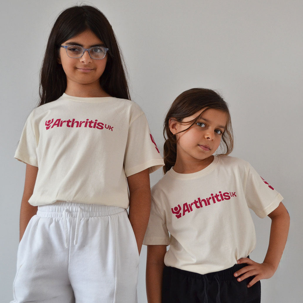 Two children wearing 'Arthritis UK' t-shirts in off-white against a plain background