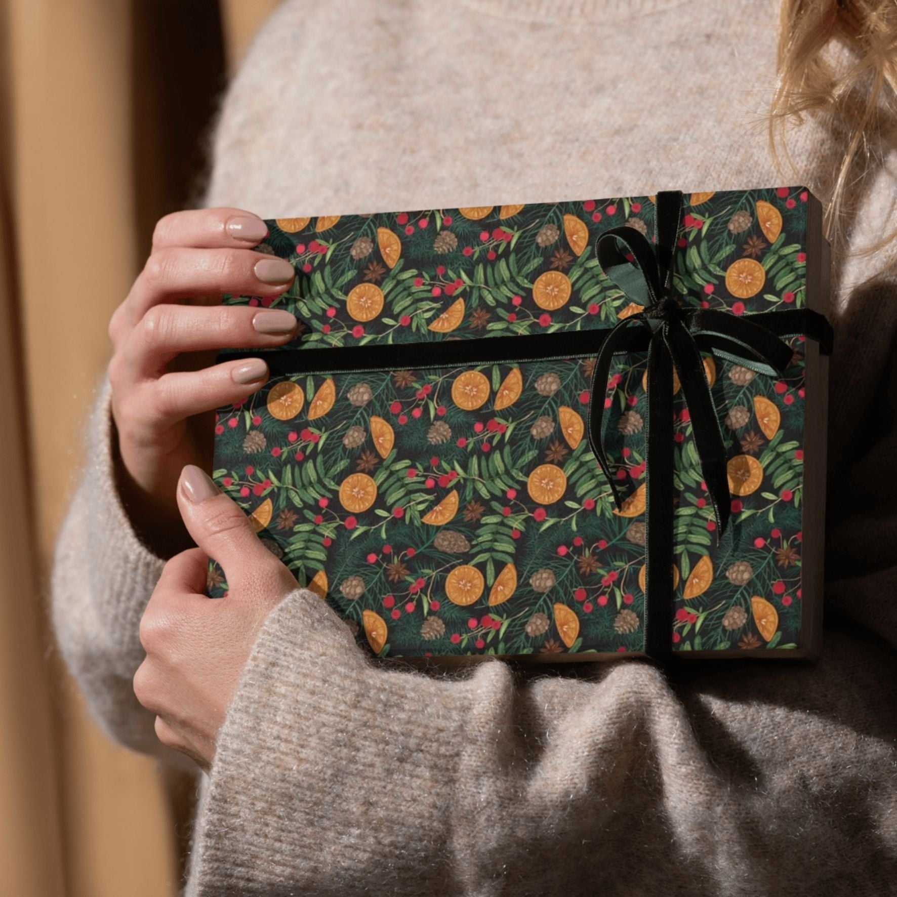 Person holding a gift wrapped in green paper with floral patterns