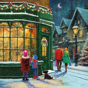 Front cover of the Arthritis UK Christmas Card 'Christmas Shop' featuring a family walking through snowy streets looking into the window of a well-lit and decorated toy shop. 