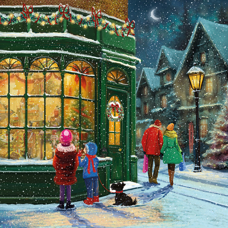 Front cover of the Arthritis UK Christmas Card 'Christmas Shop' featuring a family walking through snowy streets looking into the window of a well-lit and decorated toy shop. 