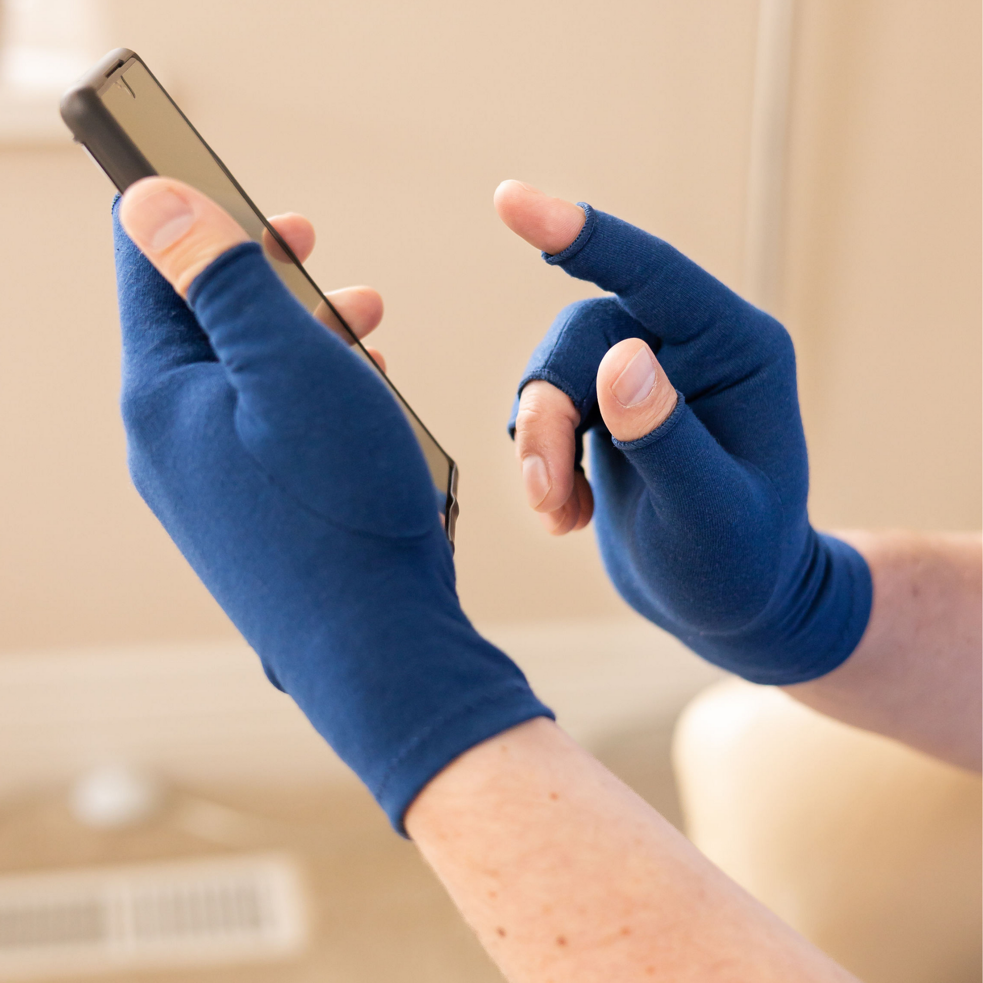 Grace and able marine blue compression gloves being worn by someone texting using a smartphone.