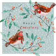 Front cover of the Arthritis UK Christmas Card 'Dotty Robins' featuring two robins wearing hats and scarves, against a snowy turquoise background, and featuring the text 'Happy Christmas'. 