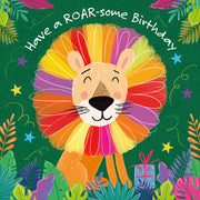 A colorful illustrated lion face with a rainbow mane on a green tropical background, with the text 'Have a ROAROsome Birthday' curved above it. The design includes palm leaves, stars, and a small gift box.