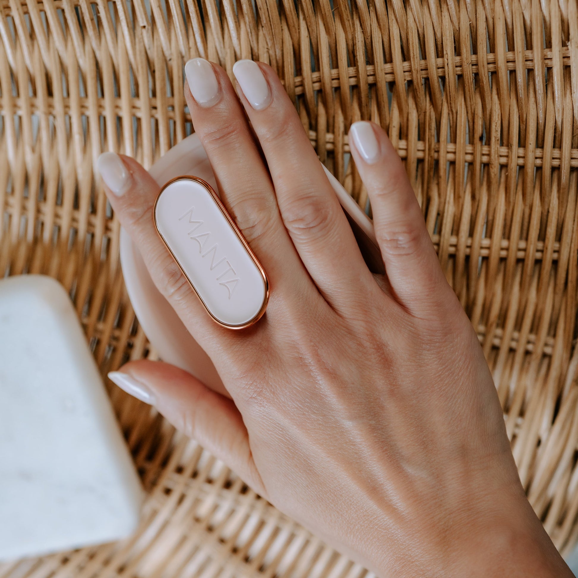 MANTA anti breakage brush in pink and rose gold, being held in a hand. 