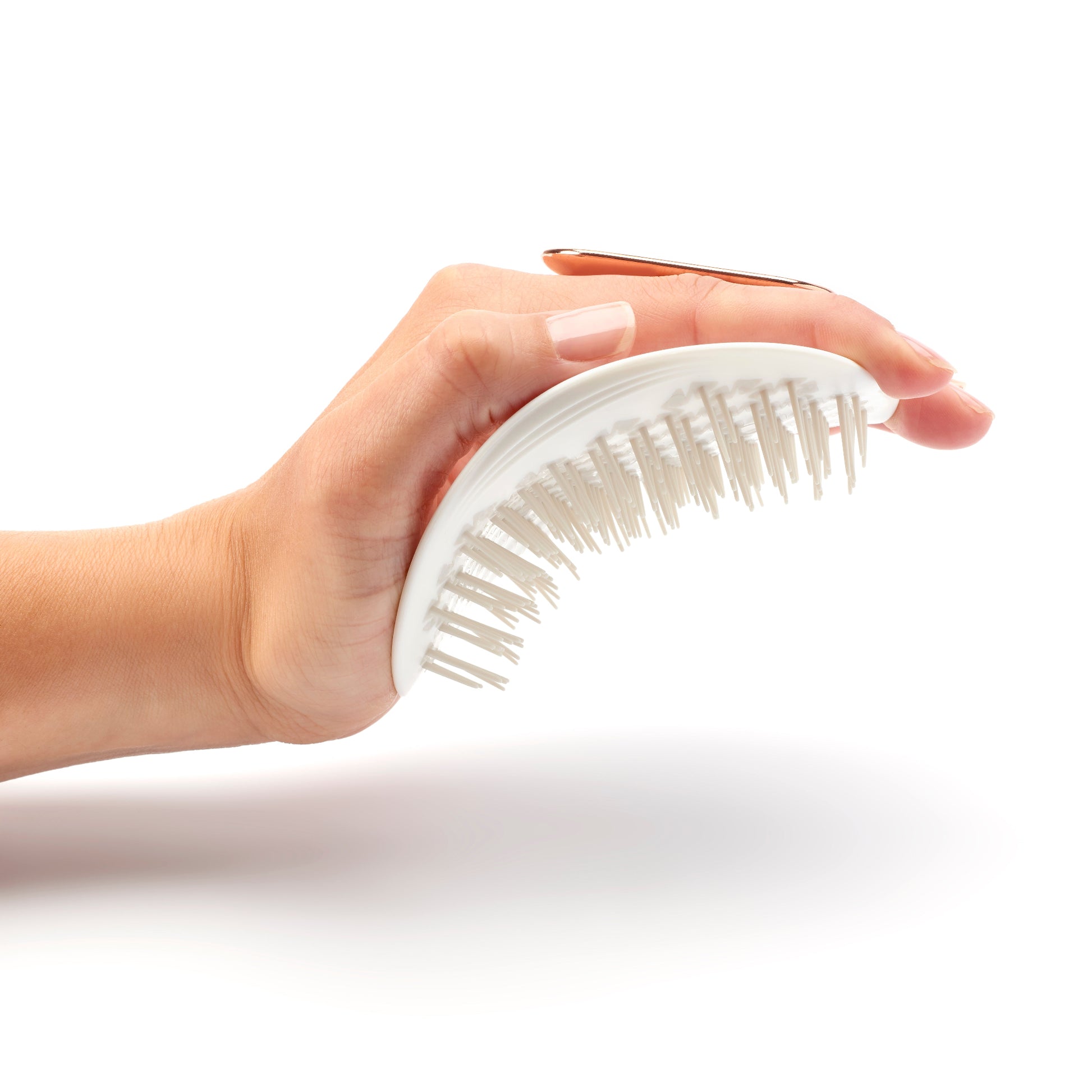 MANTA brush with a non-slip handle in white and rose gold, being flexed in the palm of the hand. 