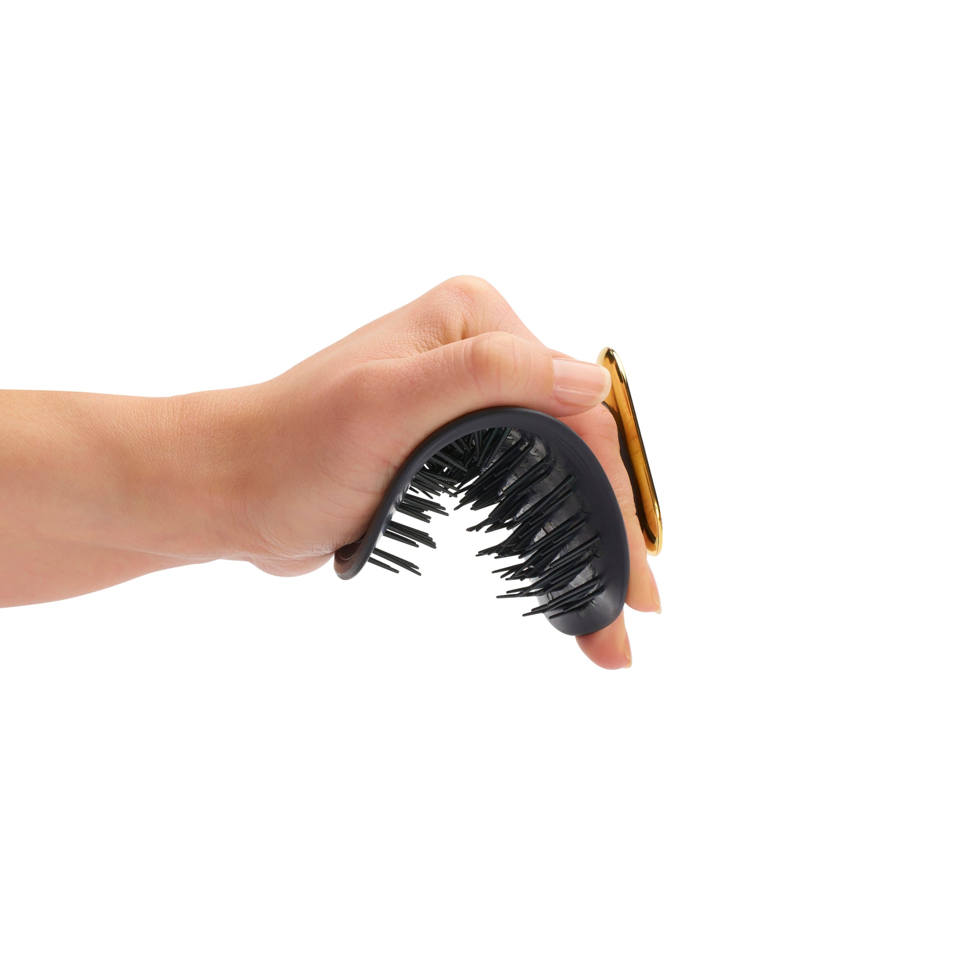 Hand holding the MANTA brush in black and gold. 