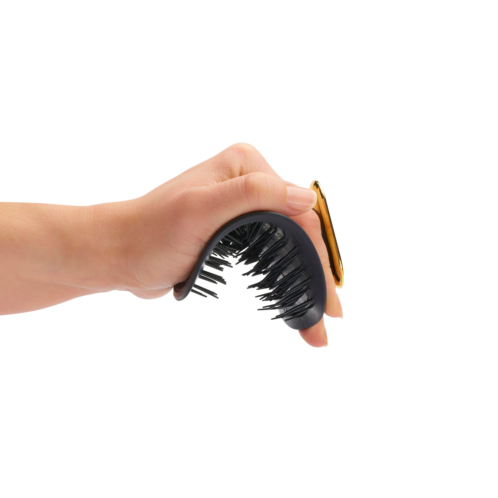 Hand holding the MANTA brush in black and gold. 
