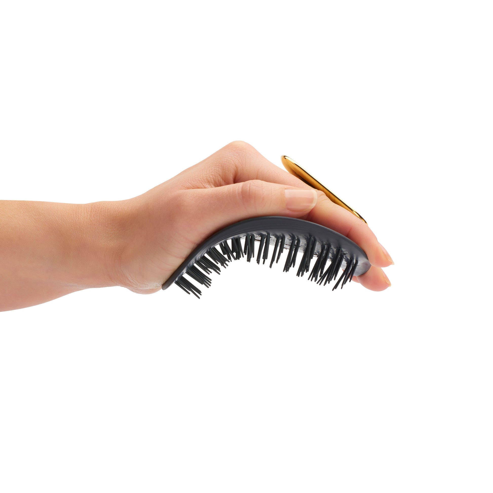 Hand holding the MANTA hair brush in black and gold. 