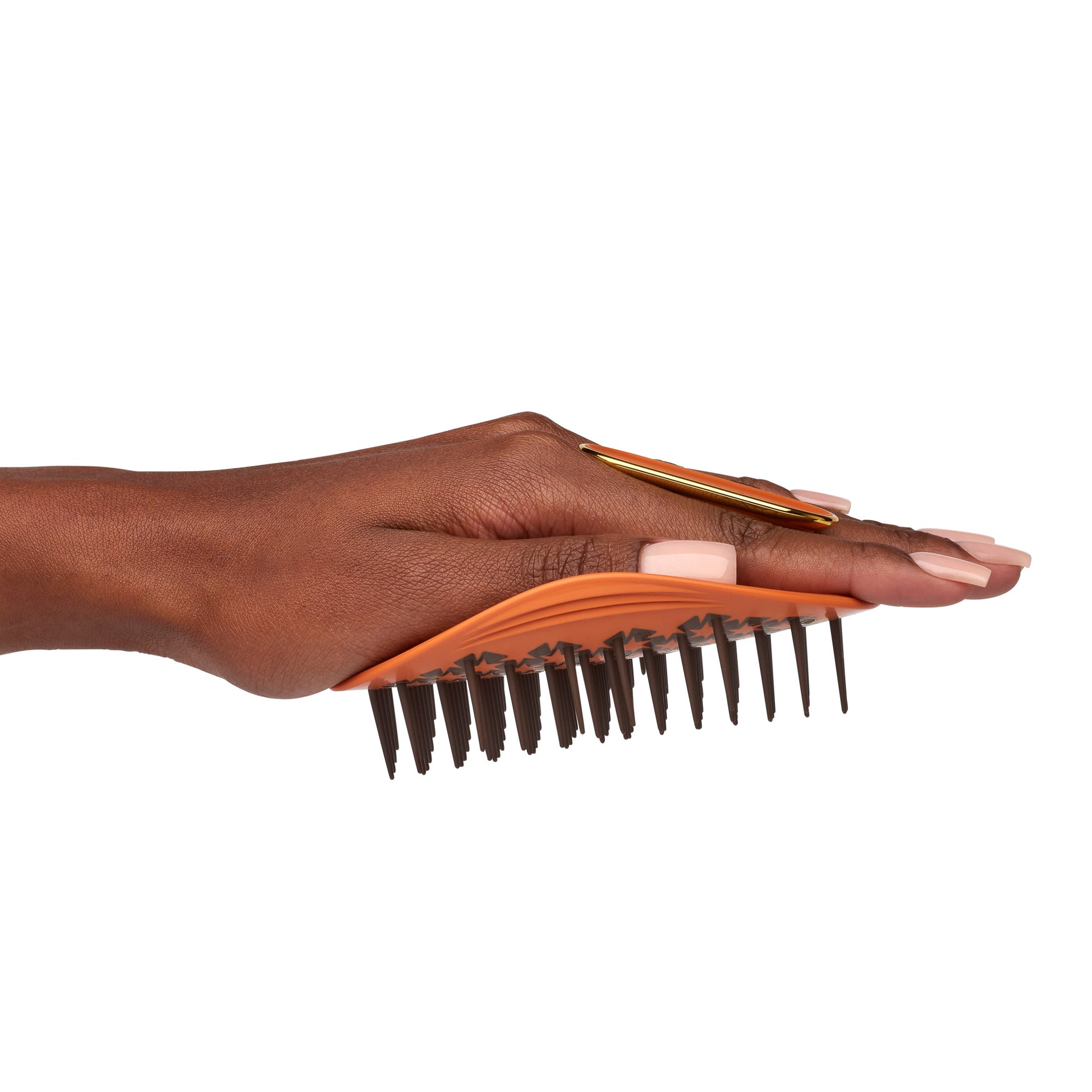 MANTA curls easy grip brush for 3A to 4C hair in amber orange, being flexed in the palm of the hand. 