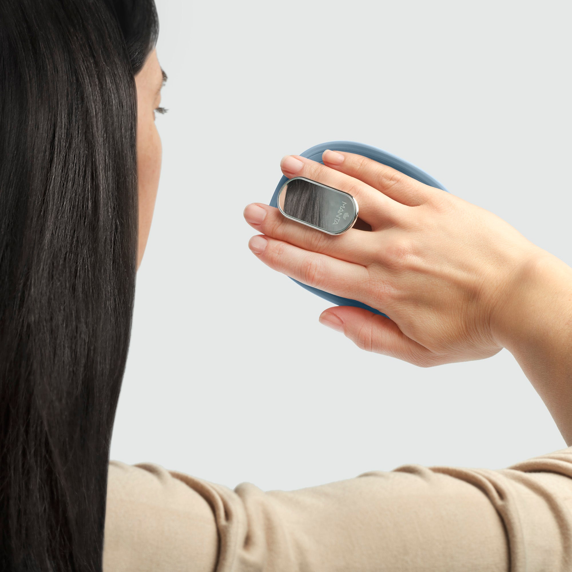 MANTA mirror travel brush with a non-slip handle in blue and white gold being held by someone looking in the mirror. 