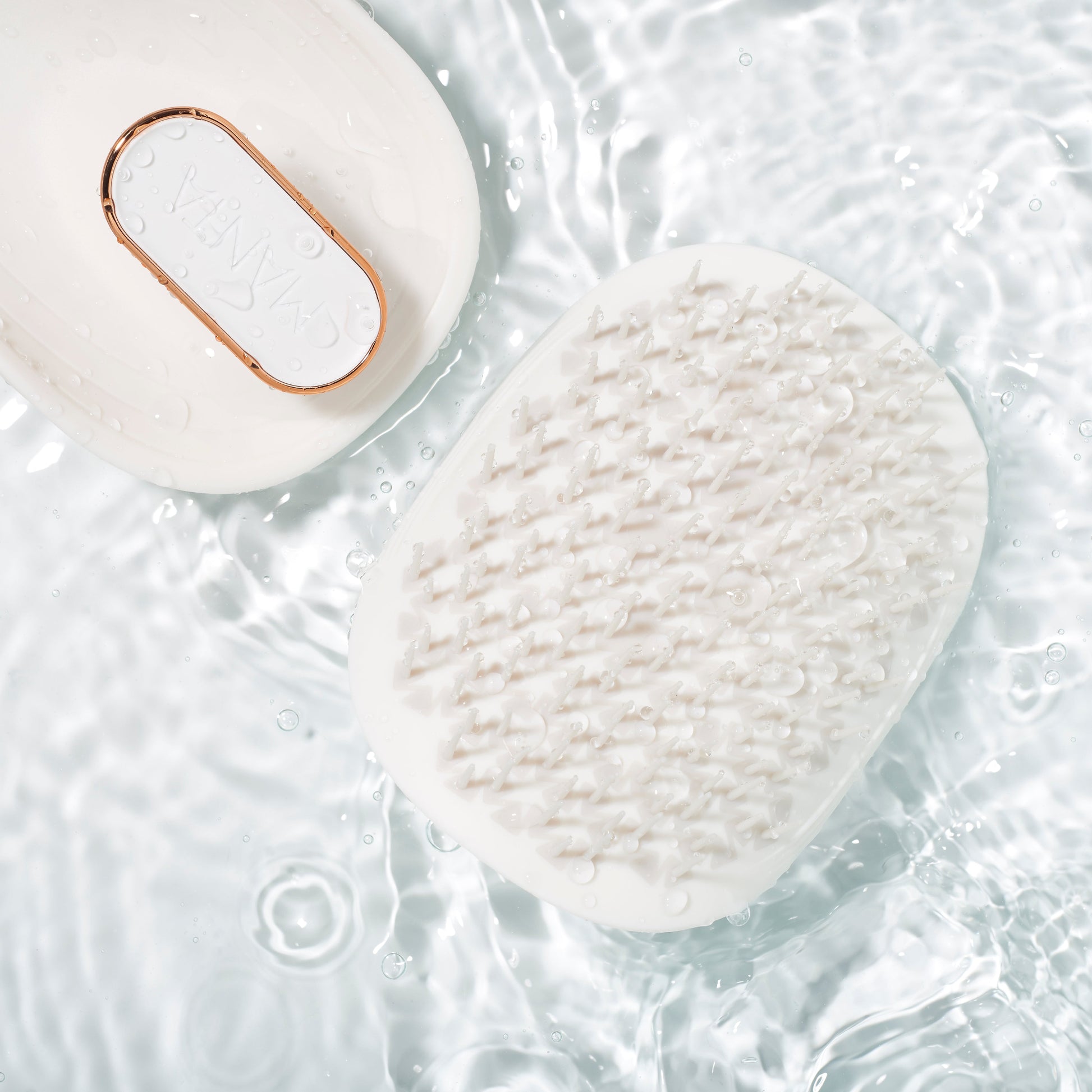 MANTA lightweight brush in white and rose gold in a pool of water.