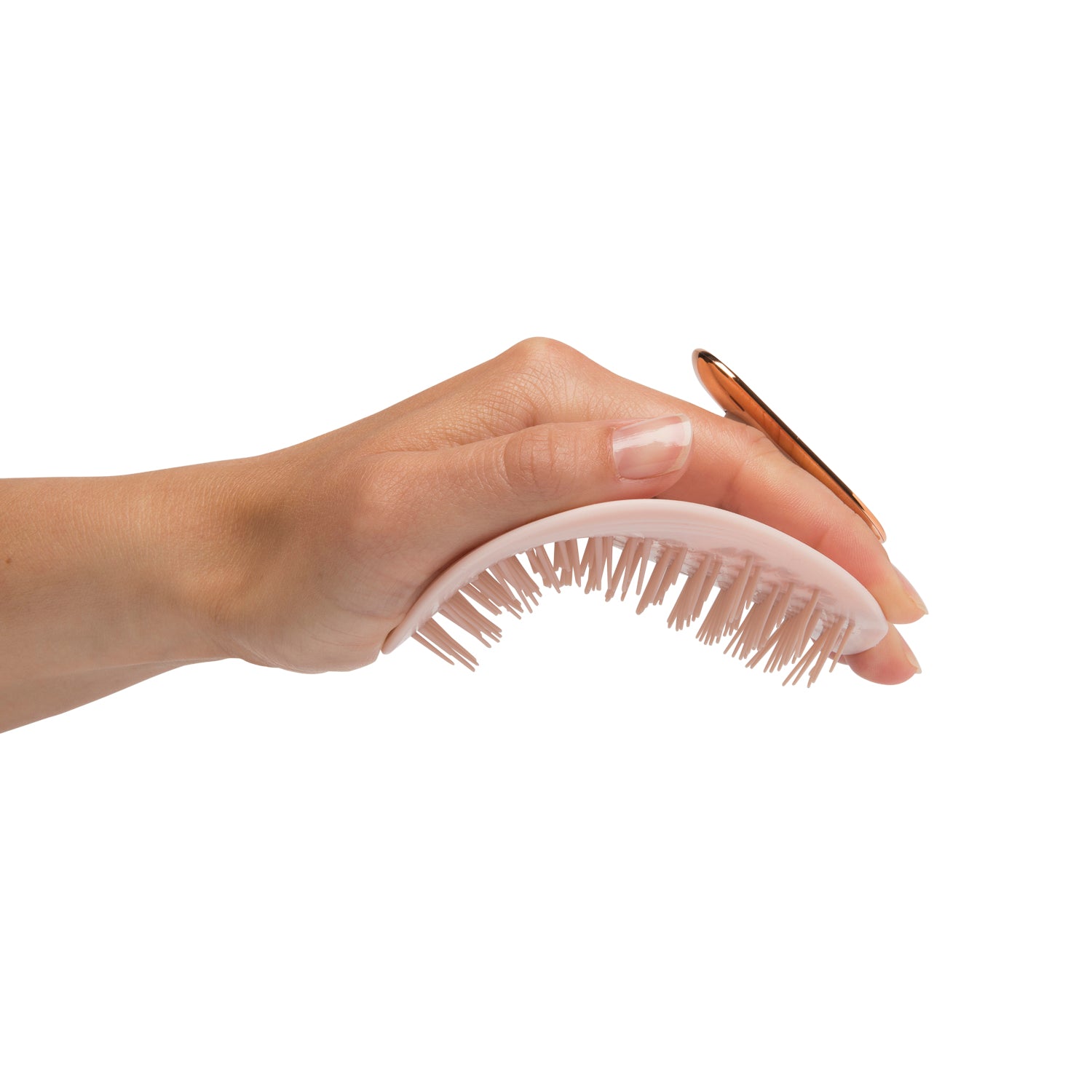 MANTA brush with a non-slip handle in pink and rose gold, being flexed in the palm of a hand. 