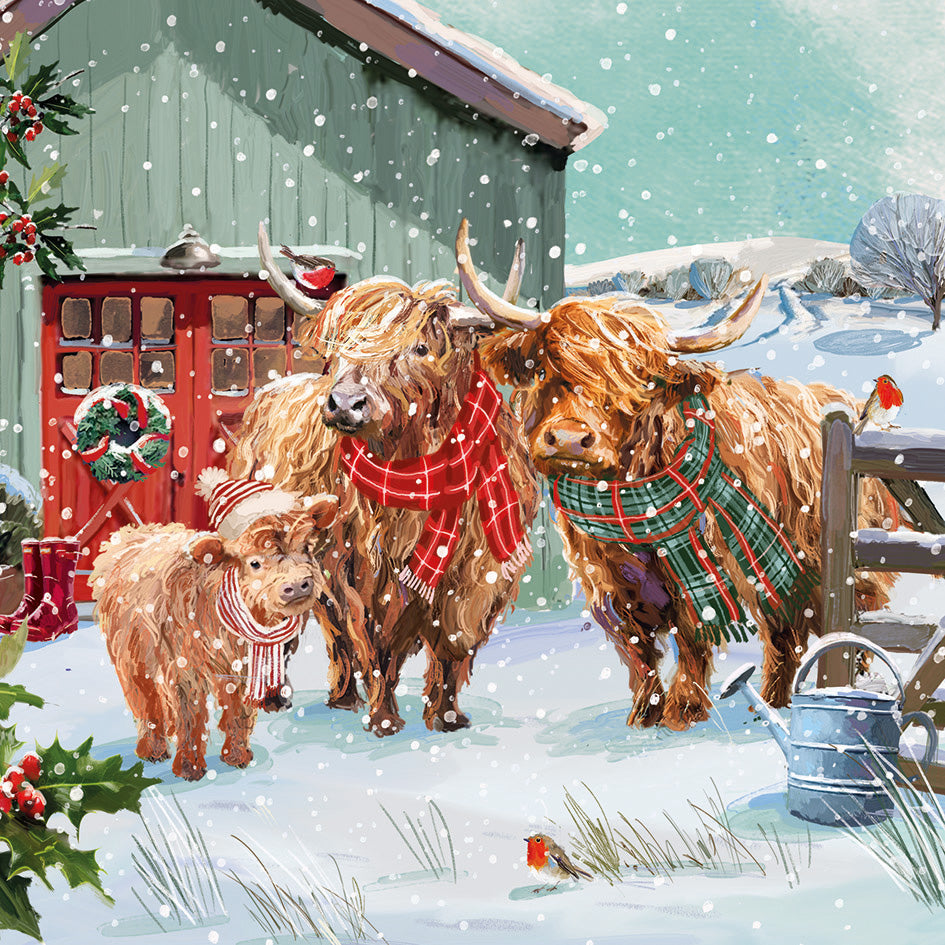 Front cover of the Arthritis UK Christmas Card 'Together at Christmas' featuring a family of highland cows, in a snowy field in front of a decorated barn. 