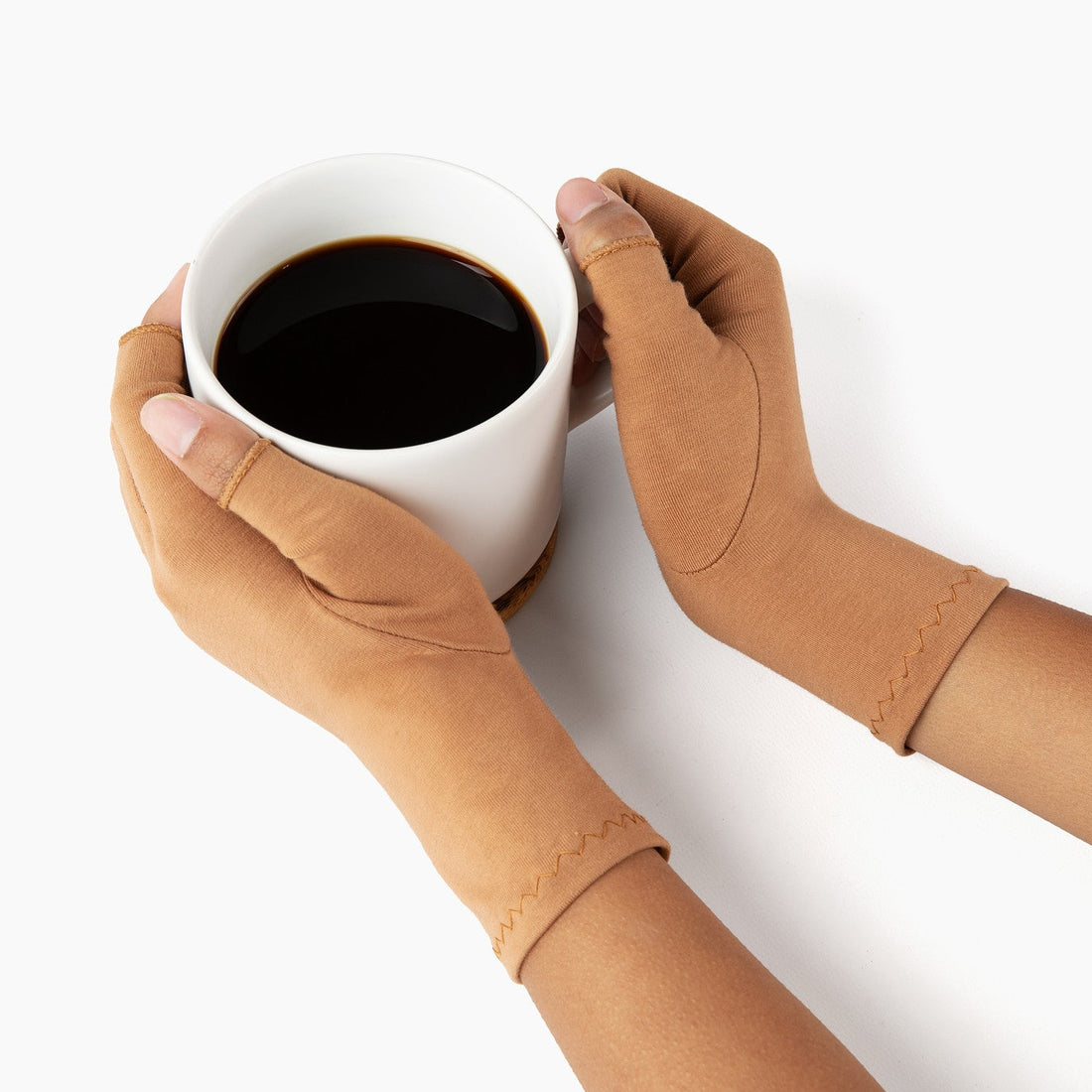 Hands wearing cinnamon brown compression gloves holding a cup of coffee