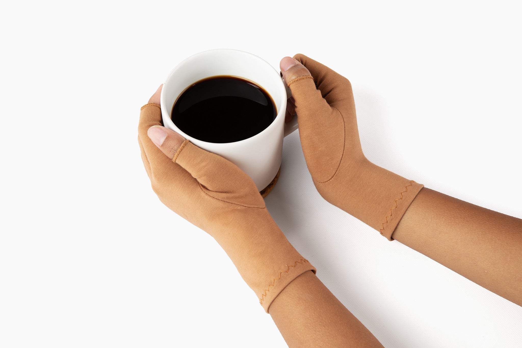 Hands wearing cinnamon brown compression gloves holding a cup of coffee