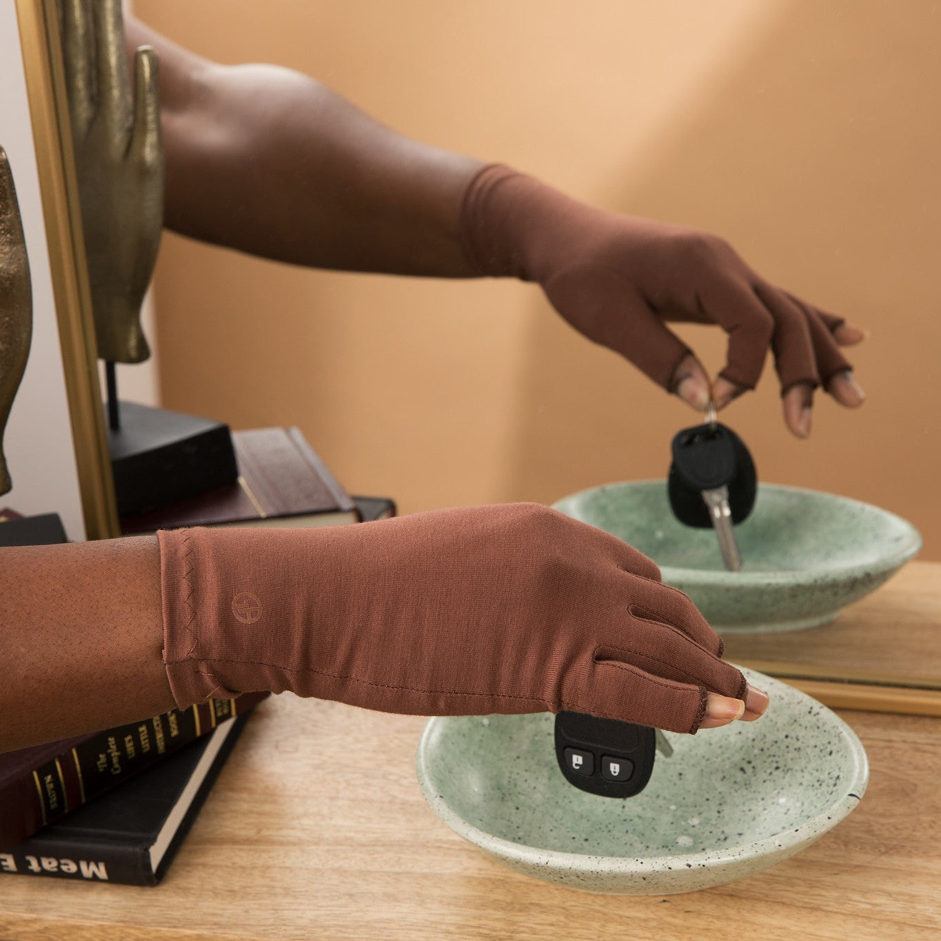 Hand wearing Grace and Able cocoa compression gloves placing keys in a bowl