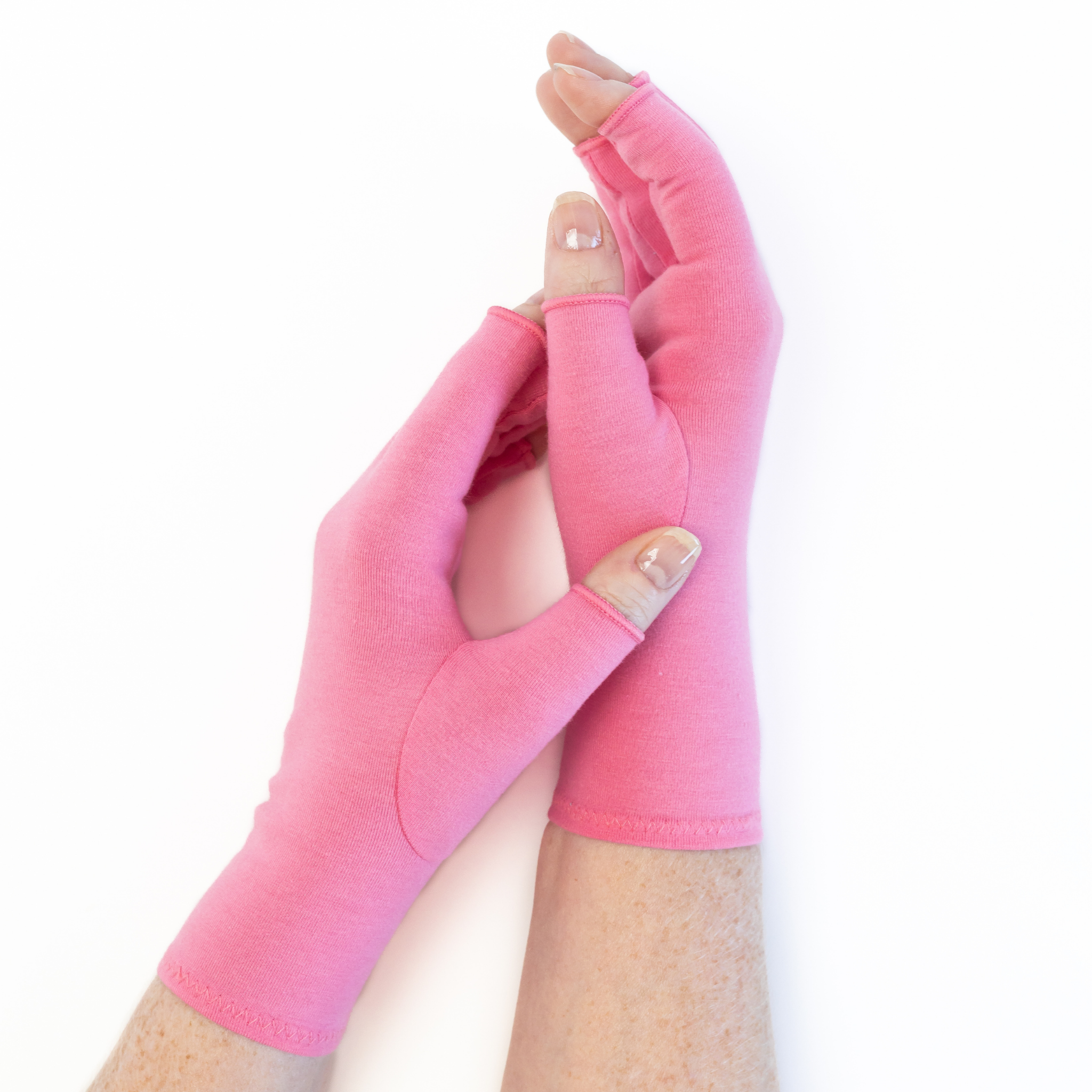 A pair of Grace and Able unisex arthritis compression gloves in coral pink, shown being worn. 