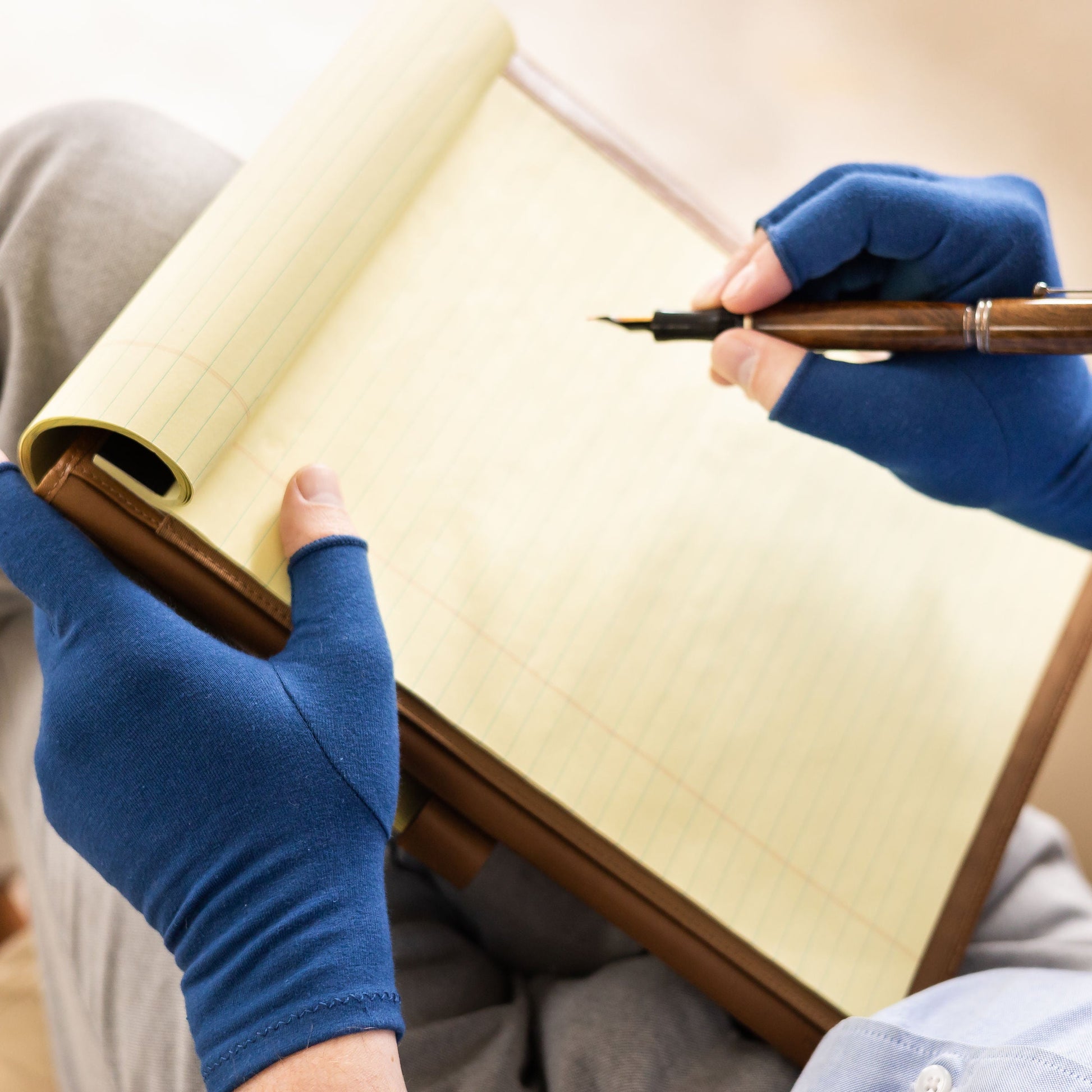 Navy blue compression gloves being used while writing on a notepad.