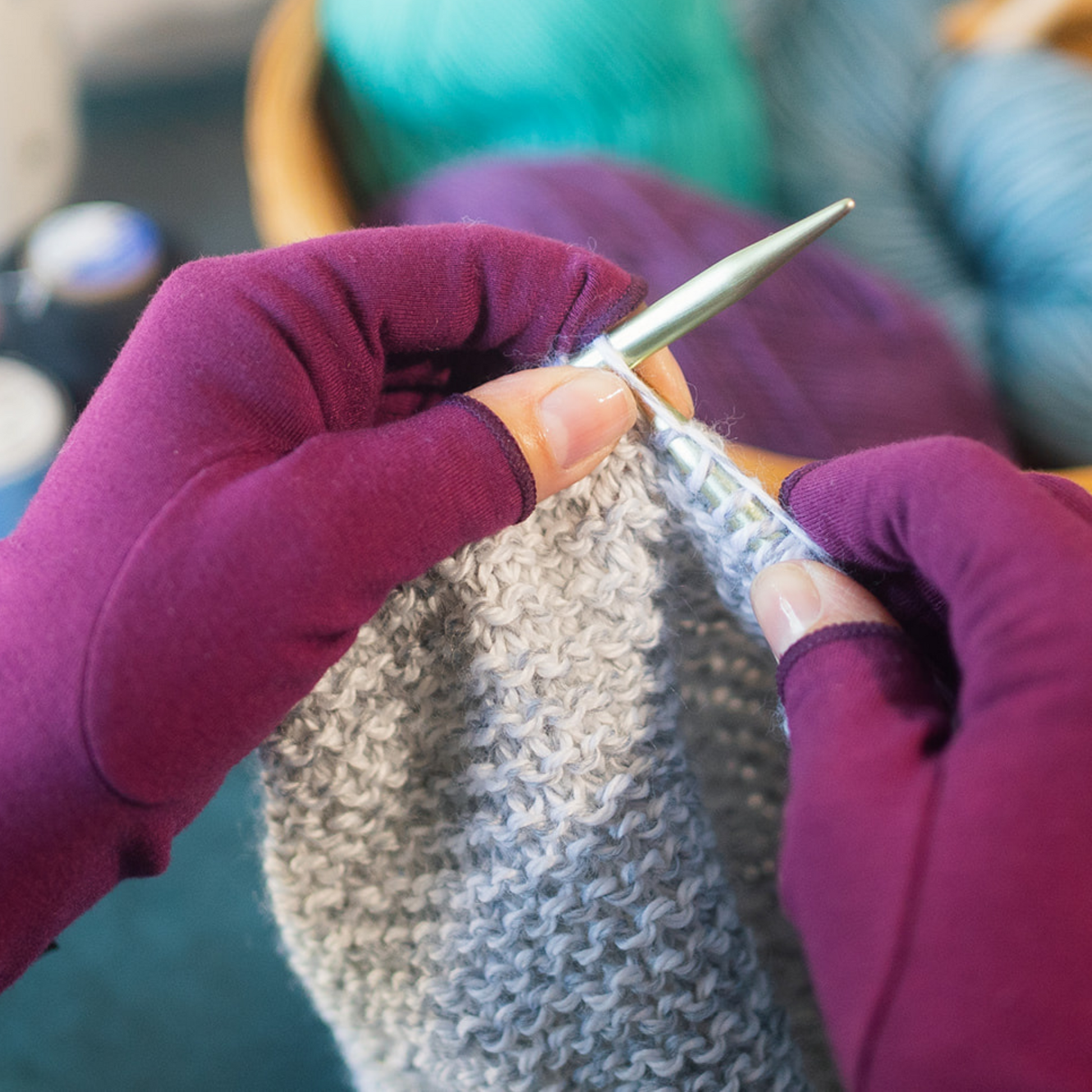 Arthritis compression gloves for pain relief shown being worn whilst knitting. Plum purple colour.