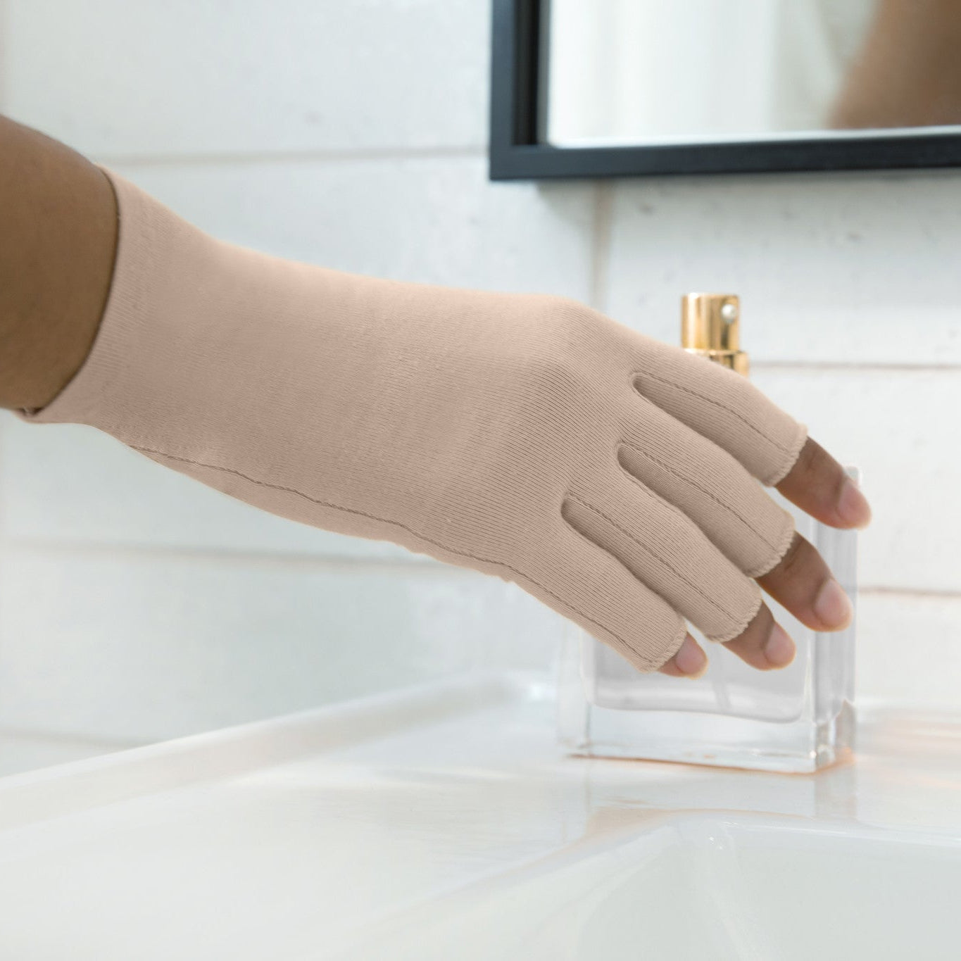 hand wearing sandy beige compression glove holding a perfume bottle