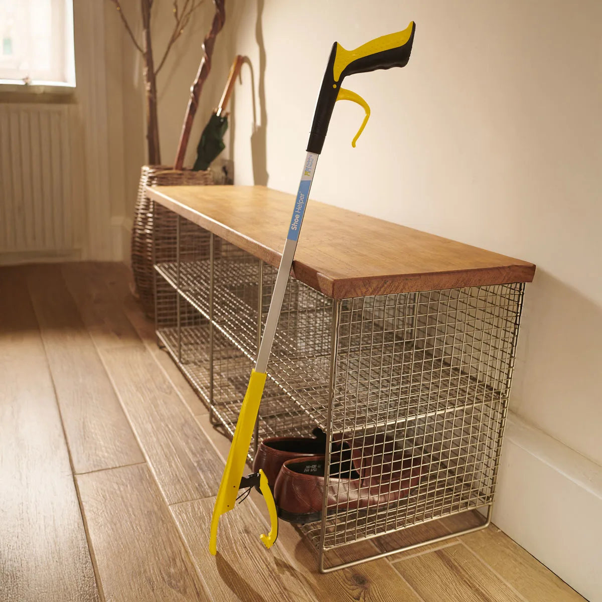 Shoe helper reacher grabber leant against a shoe rack. 